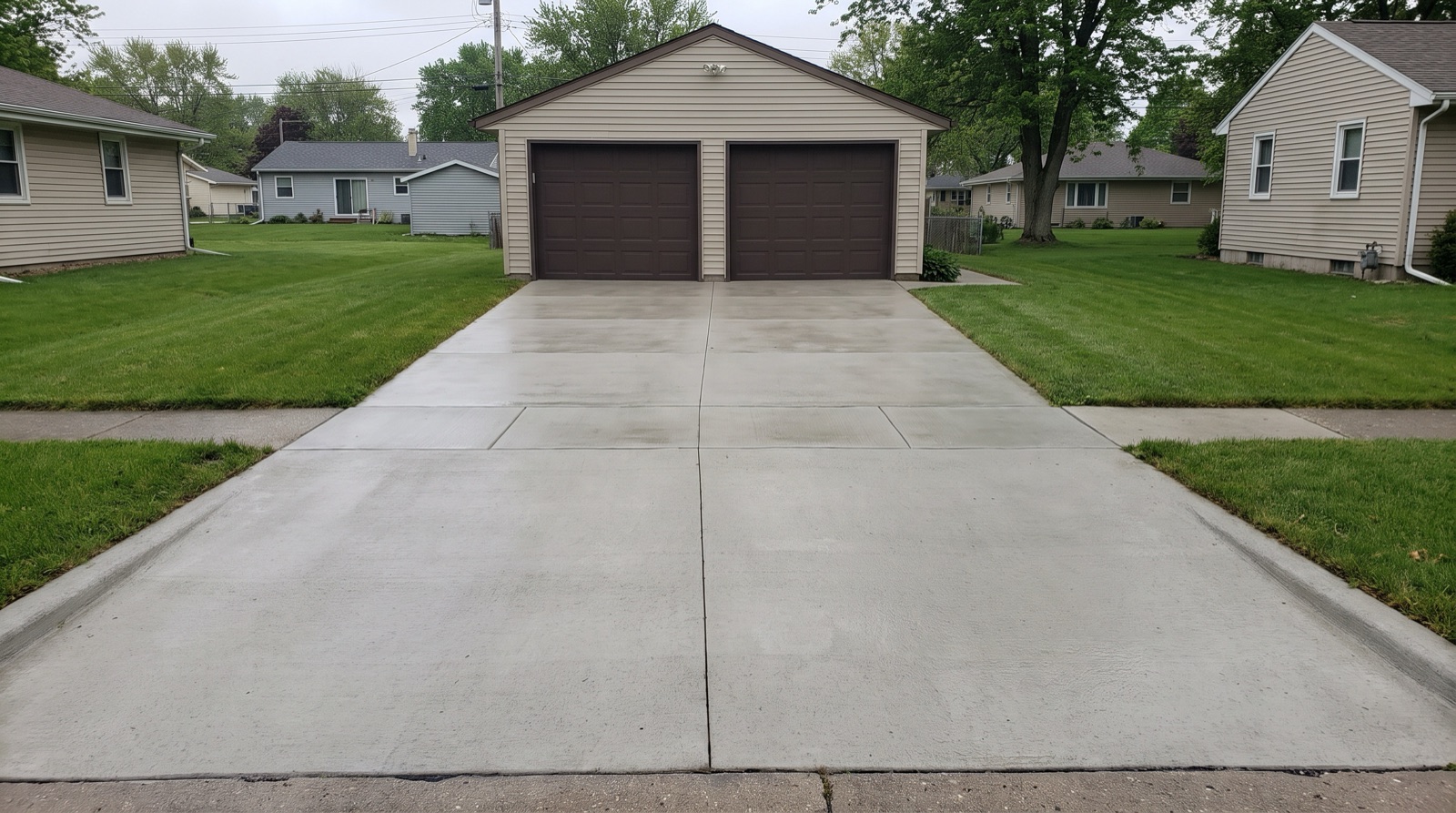 A clean, evenly washed concrete driveway leading to a suburban garage