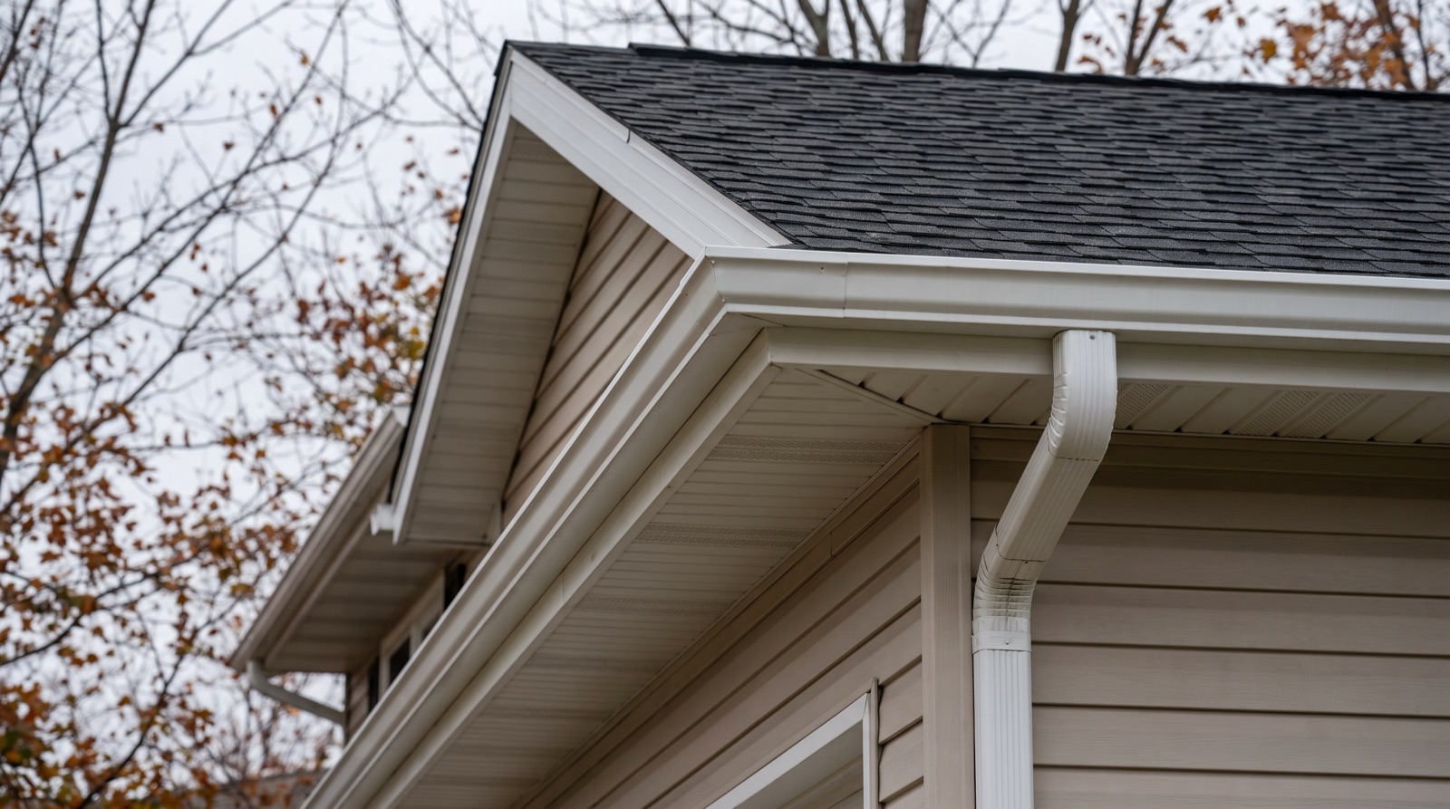 Clean, freshly cleared white gutters and downspout on a Columbus home